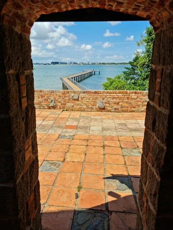 looking out at a dock from an arched doorway in a brick wall
