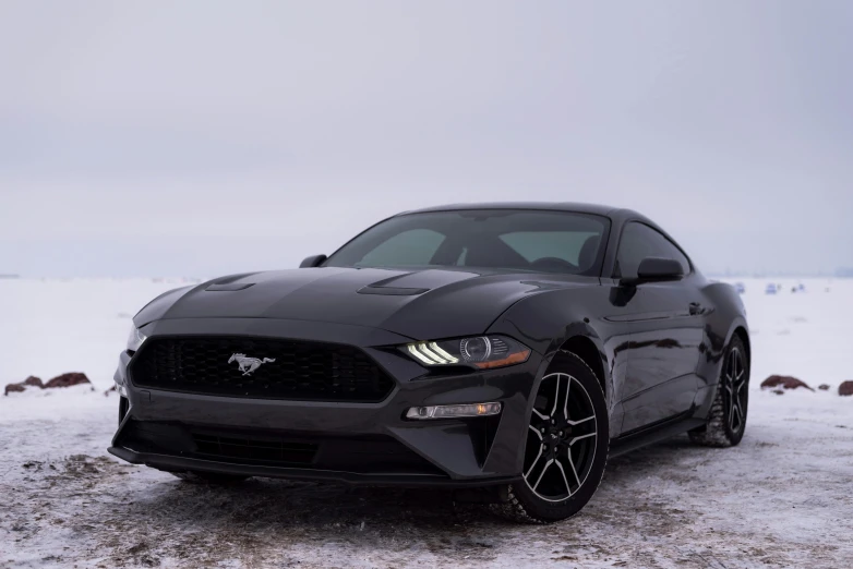 a mustang parked in the snow on a lot