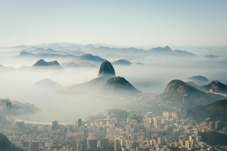 a bird's eye view of mountains and fog with buildings on either side