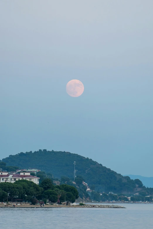 full moon above an island with trees on top