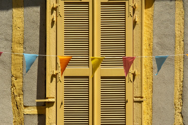 the yellow shutters are covered by colored flags