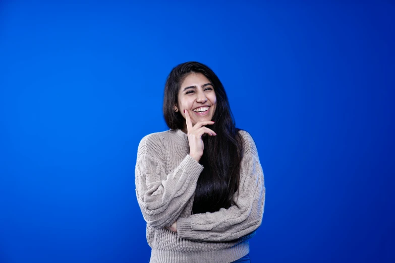 woman standing with hand under her mouth smiling for camera