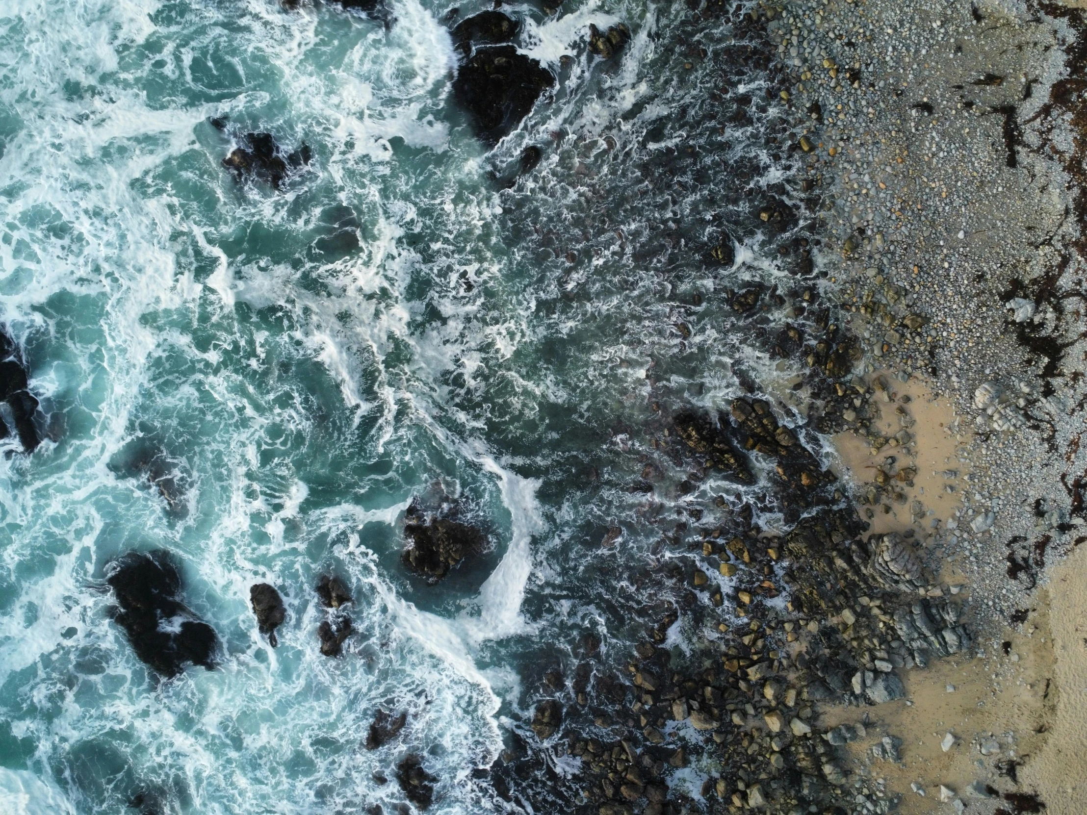 an aerial view of the ocean and rocky shoreline