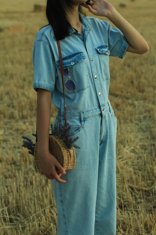 a girl with long hair in a blue jumpsuit holding a wicker basket