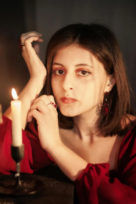 a woman in red sitting at a table with a candle