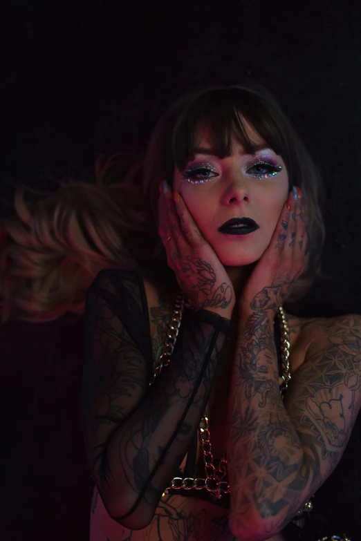 a woman with tattoos and piercings with her hands behind her face