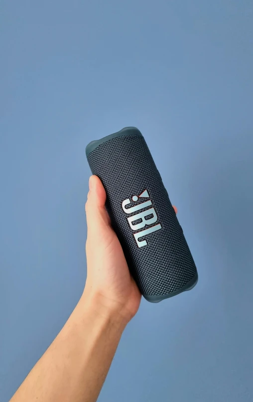 a hand holding up a very large wireless speaker