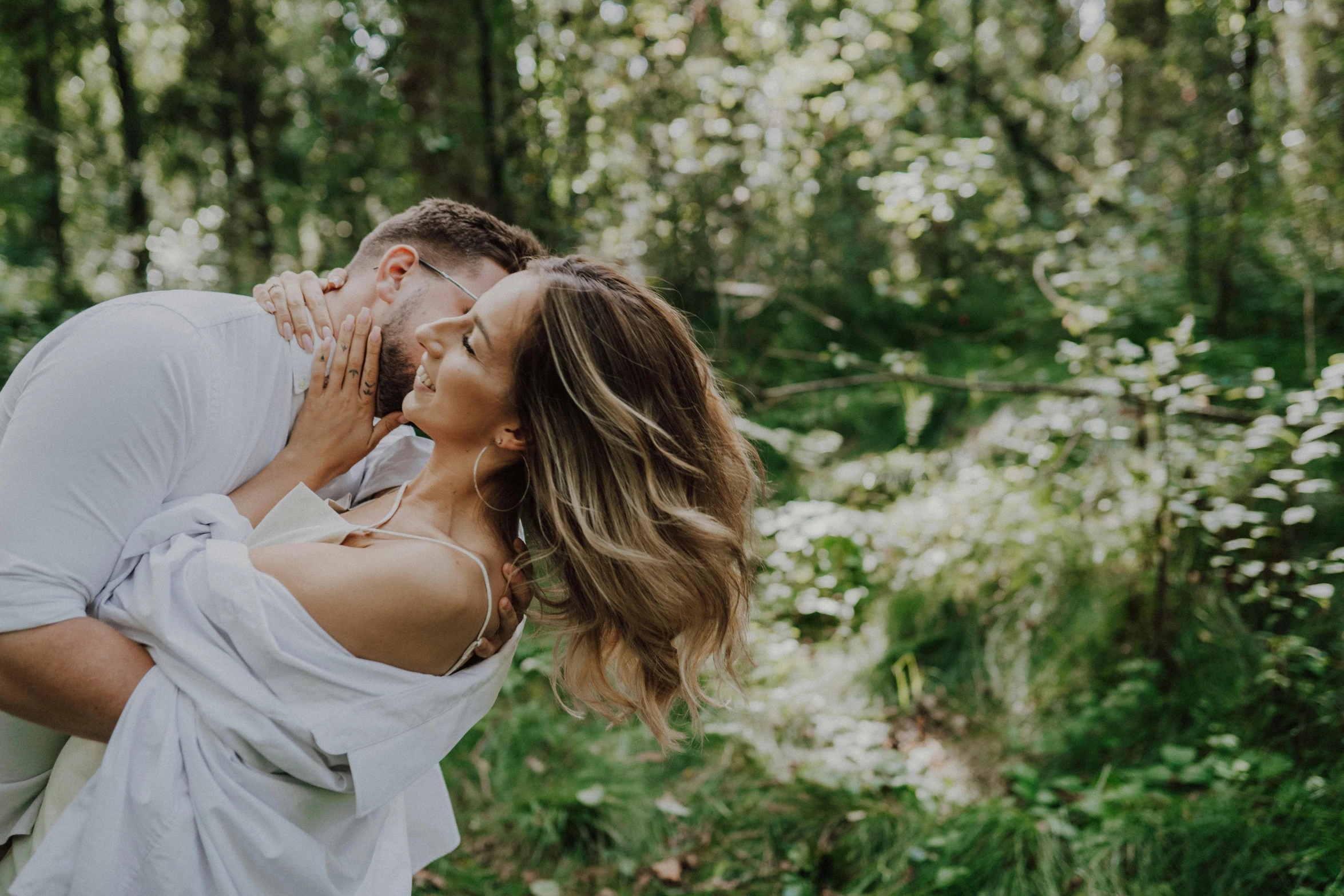 a man and woman are kissing in the woods