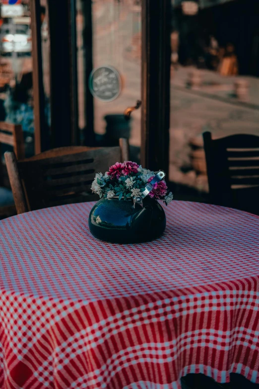 a black vase filled with pink flowers sitting on a table