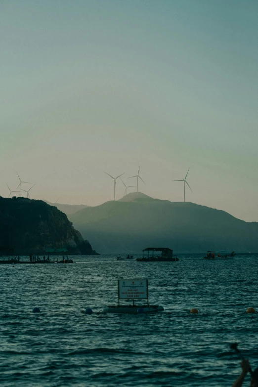 wind turbines are seen along side a mountain and ocean