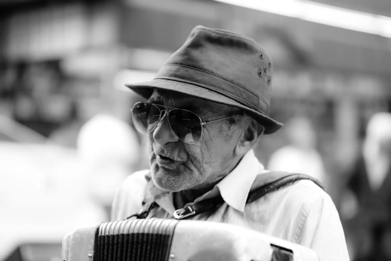 a man in sunglasses playing an accordian with a hat