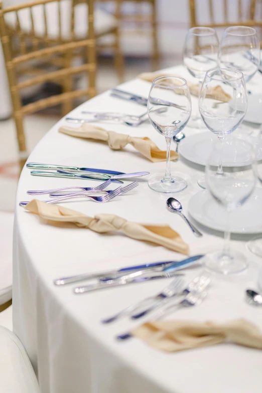 a table with wine glasses, silverware and plates