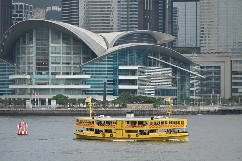 a yellow and black passenger boat in front of some buildings