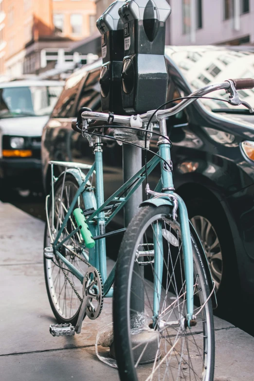 a green bike parked near a parking meter