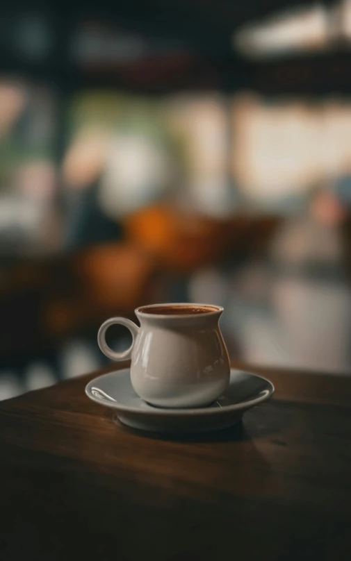 a coffee cup sits on a table in front of a blurry background