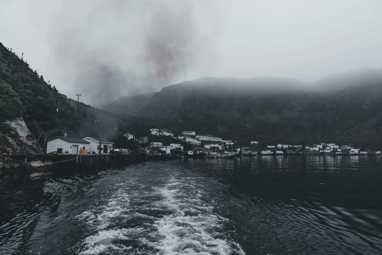 a river flowing under the cloudy sky near some houses