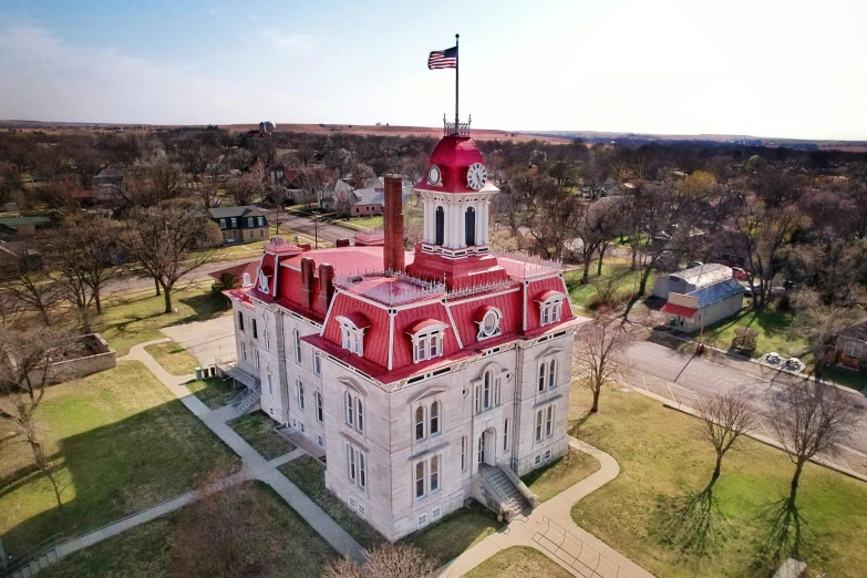 a old church with a red roof surrounded by trees and grass