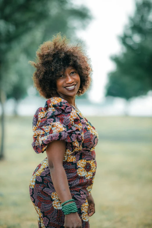 a woman smiling and standing in the middle of the park