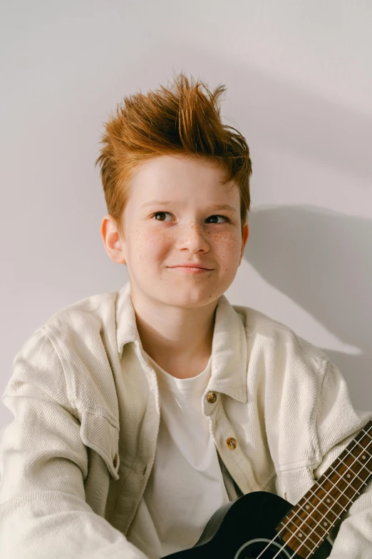 a boy with red hair is smiling and playing a guitar