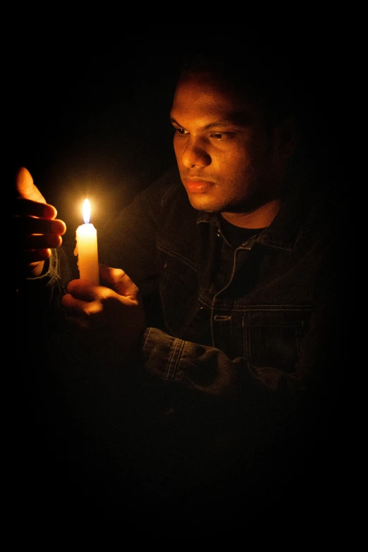 a person holding a lit candle while staring at it