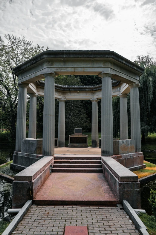 an outside gazebo with steps up to it and a bench by the water