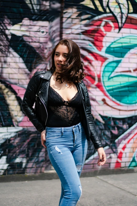 a woman posing for the camera in front of some graffiti