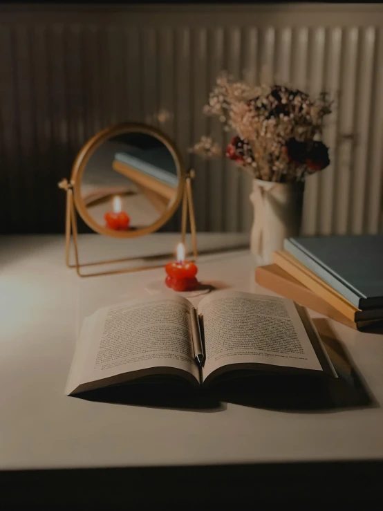 an open book sitting on top of a table next to a mirror