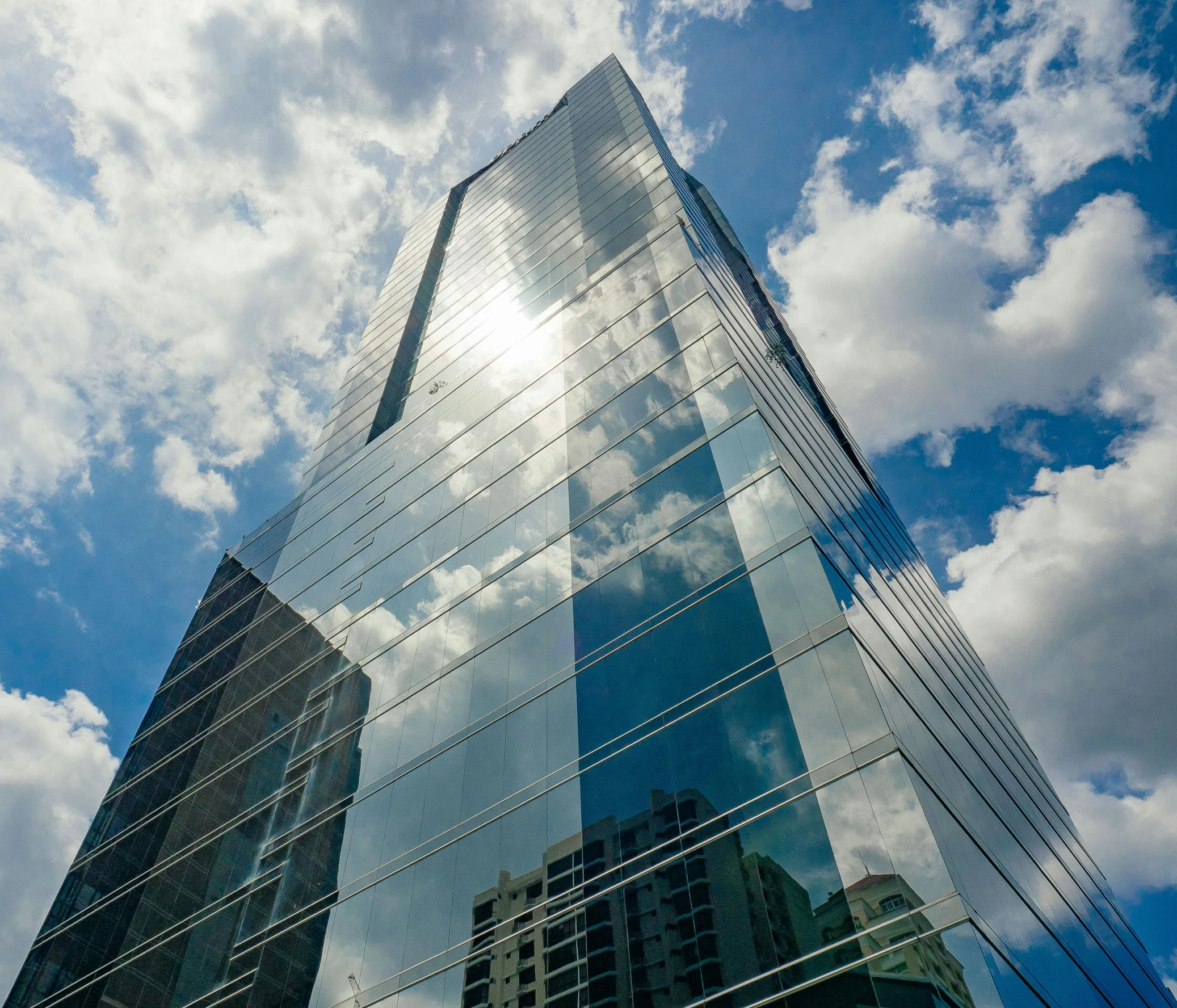 the side of a building reflecting clouds in its windows