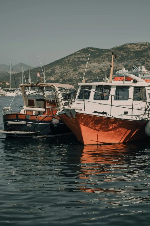 two boats are docked on the water in front of a mountain