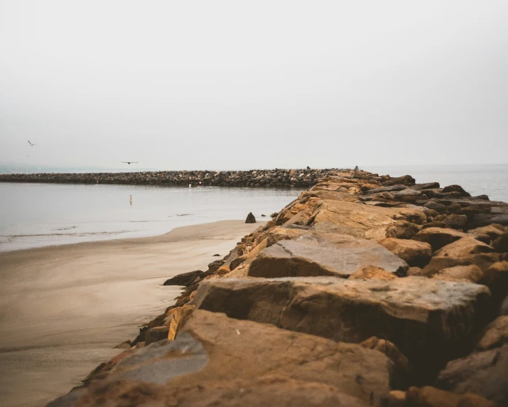 a beach covered with rocks and water in the background