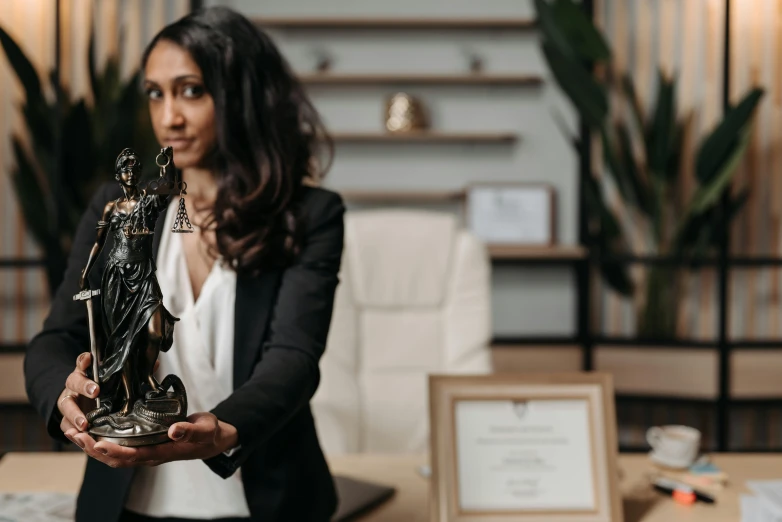 a woman is holding up a statue of a sailboat in front of a laptop