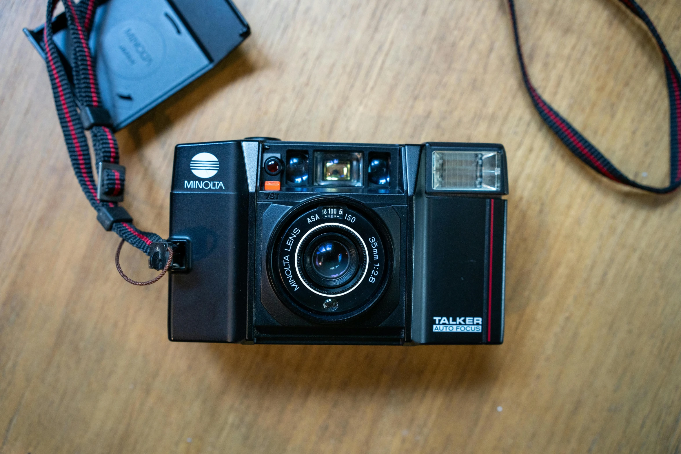 an old camera with a strap is resting on a wooden table