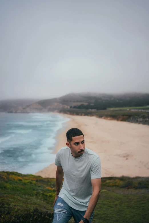 a man in jeans walking along the beach