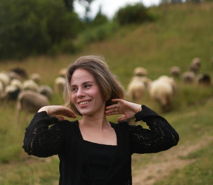 a beautiful woman standing next to sheep in a field