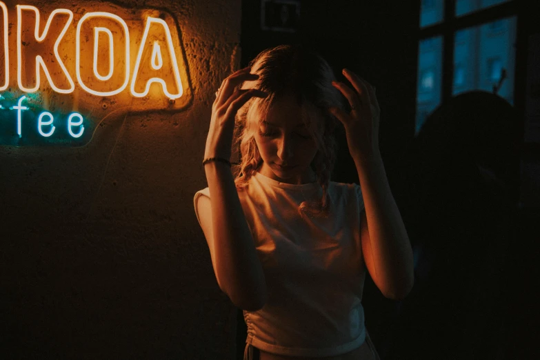 woman in white shirt holding her head next to a neon sign