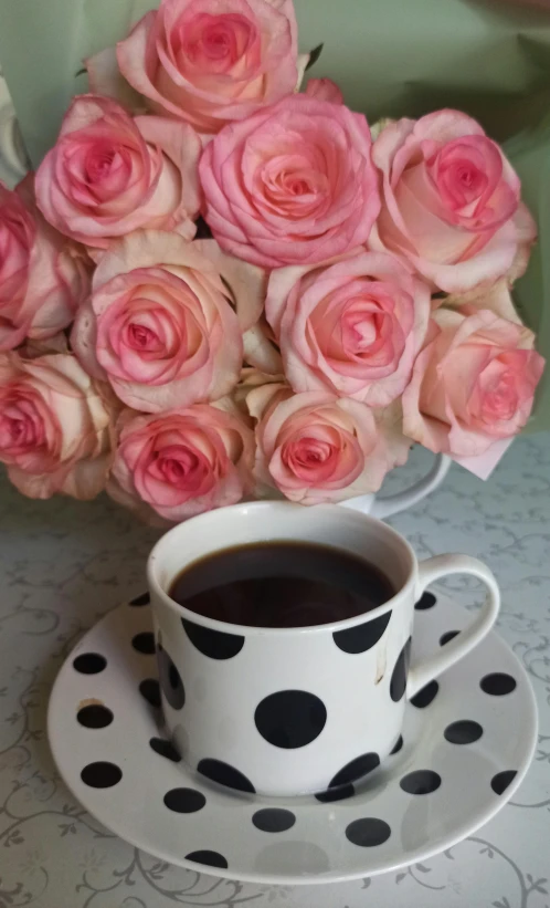 a polka dot coffee cup filled with pink roses