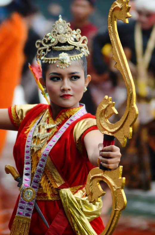 a woman in a gold and red costume holding an instrument