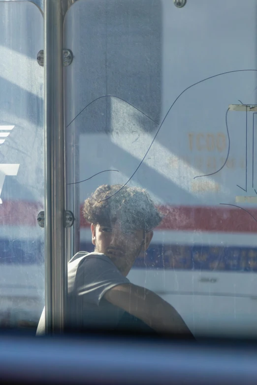 man sitting in a bus behind glass that has the words aeroplane written on it