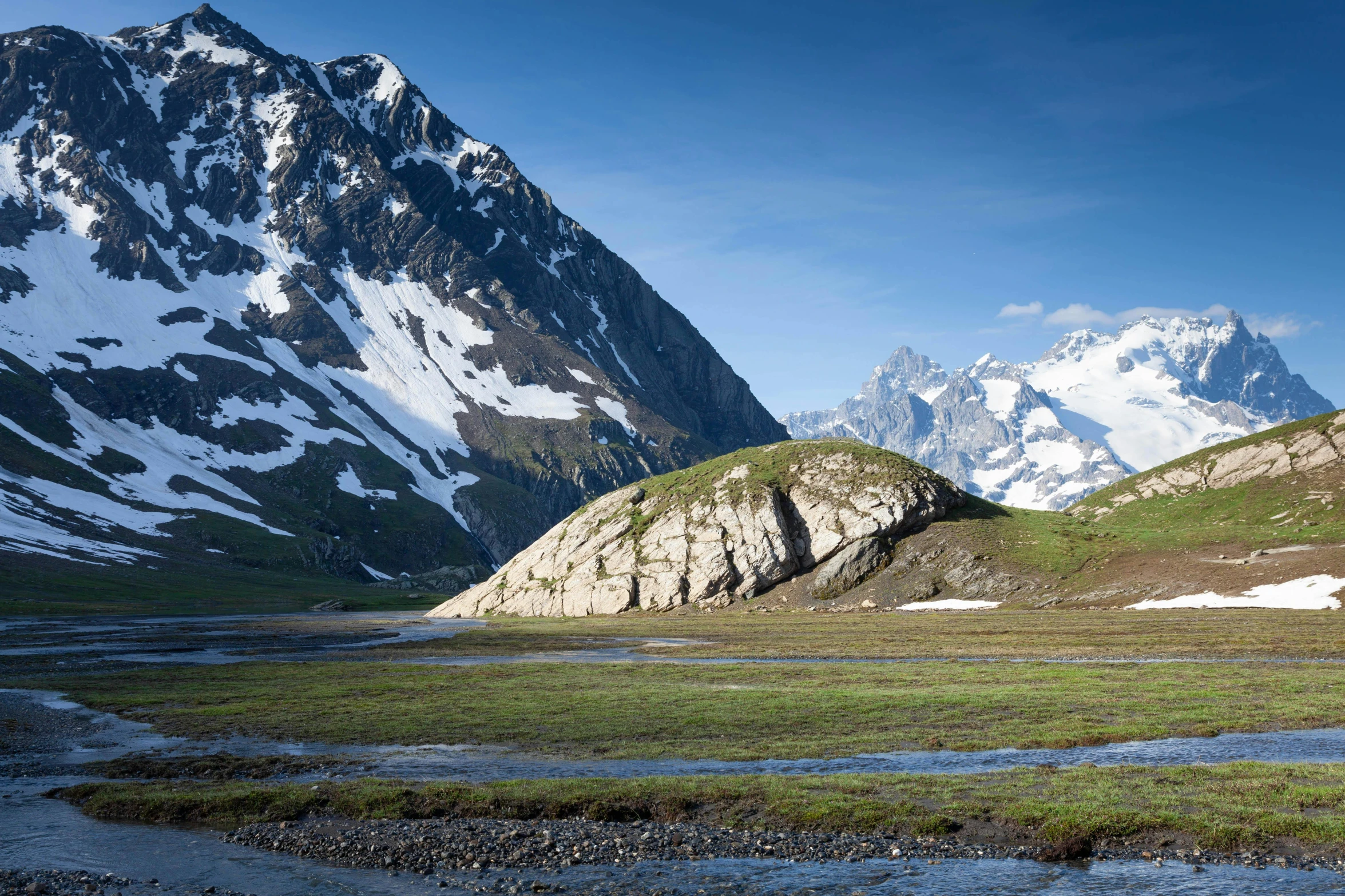 the mountains are covered with snow and green grass