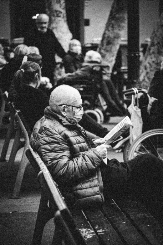 black and white pograph of a man on a bench reading