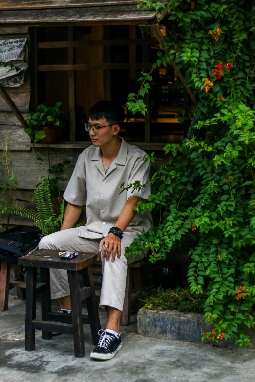 a man sitting on a bench near a bush