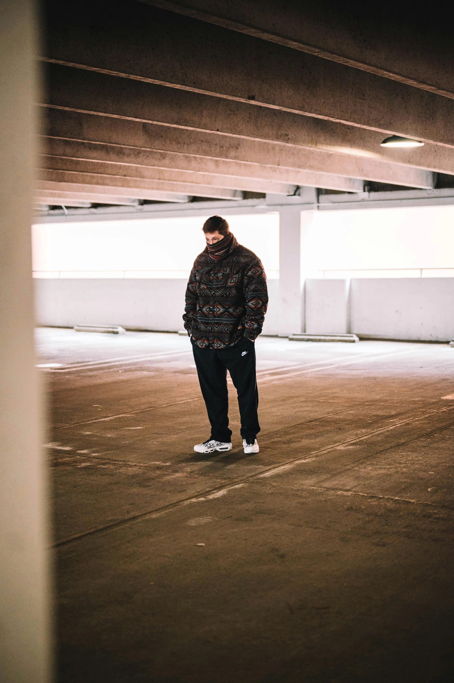 there is a man standing in an empty parking garage