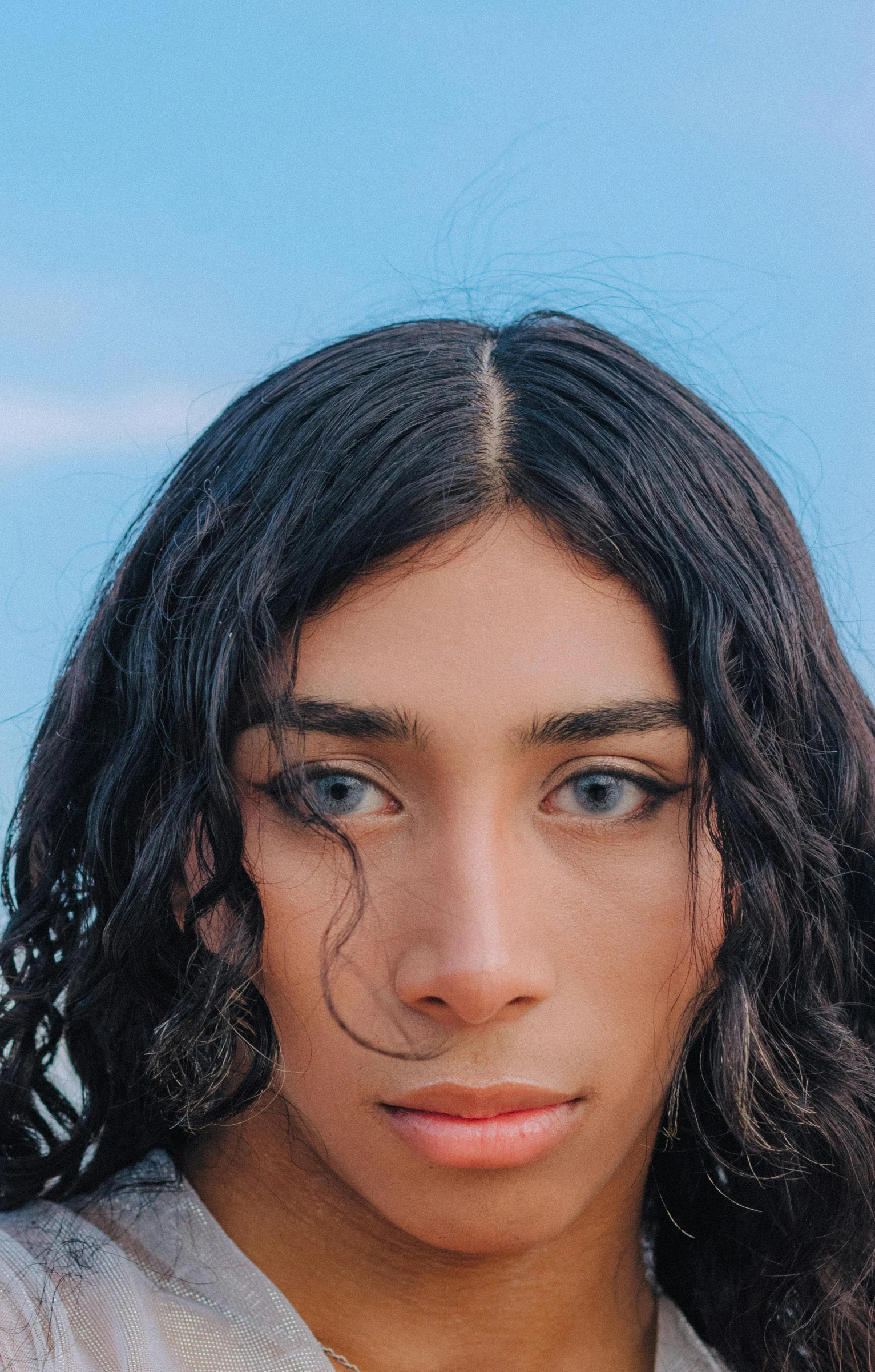 a woman with long hair looks into the camera