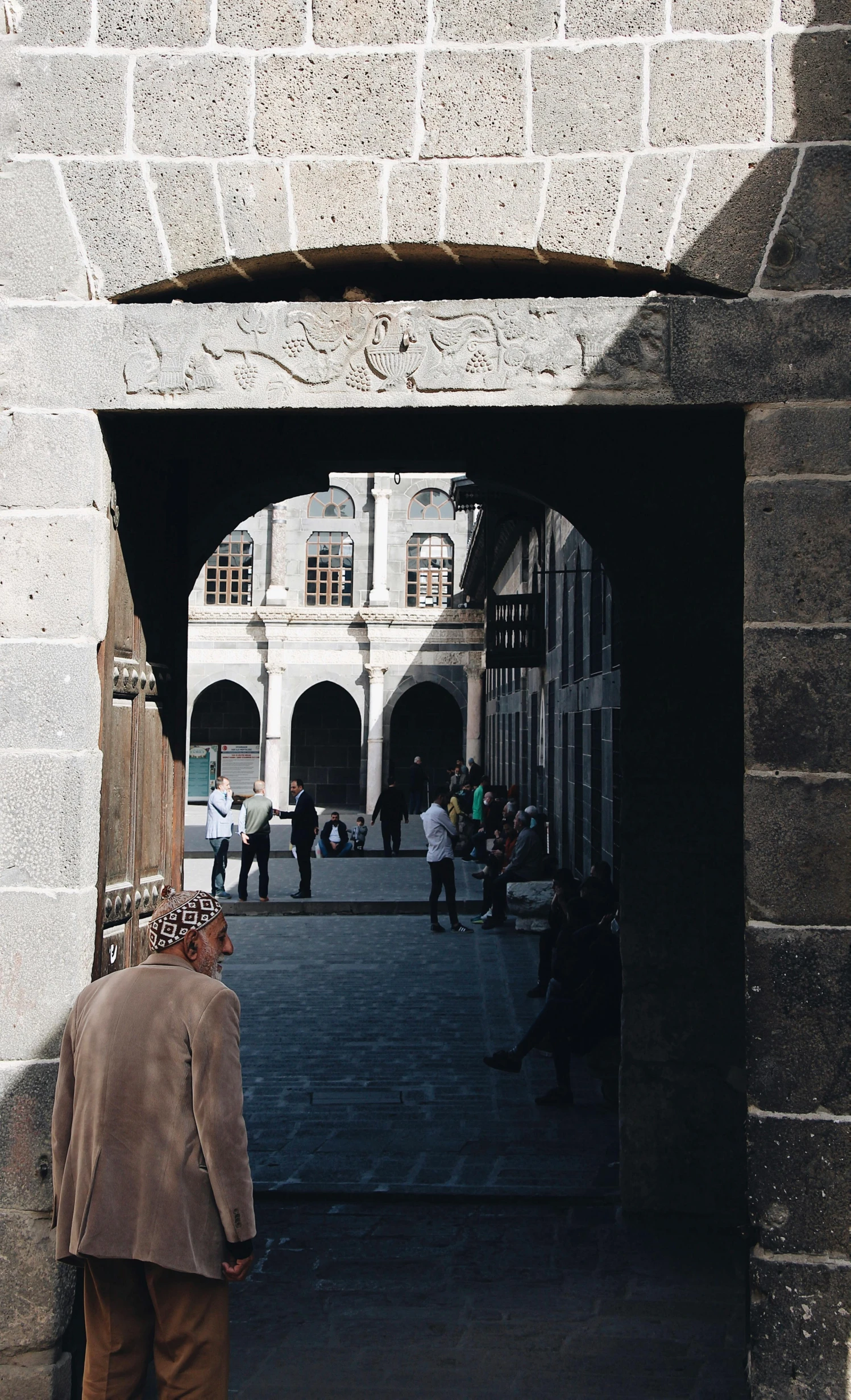 people entering and exiting an old building, with archways