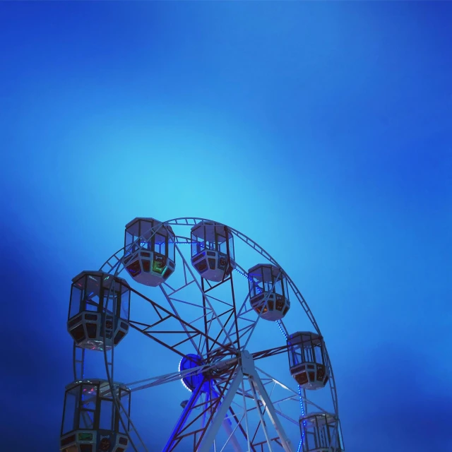 the ferris wheel has many lights and a blue sky