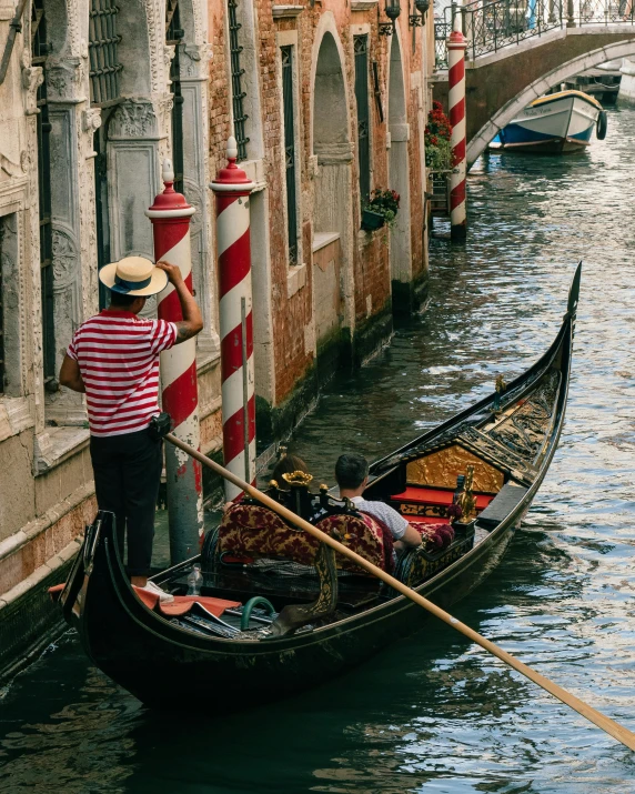 man on gondola holding his hat while another person is standing near