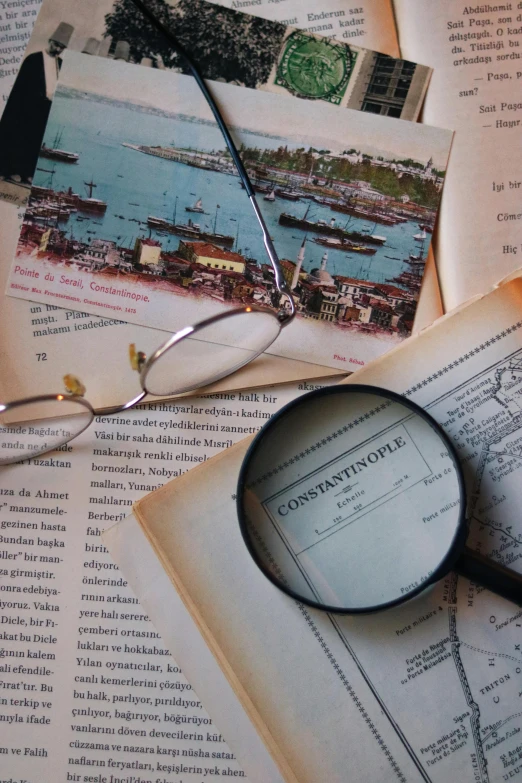 an opened book has pictures of boats and a magnifying glass on top of it