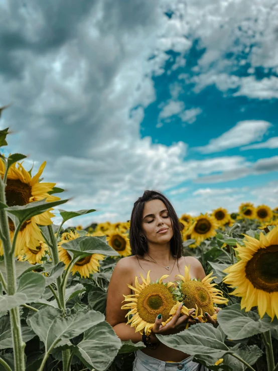 a woman with sunflowers in her hands on a cloudy day