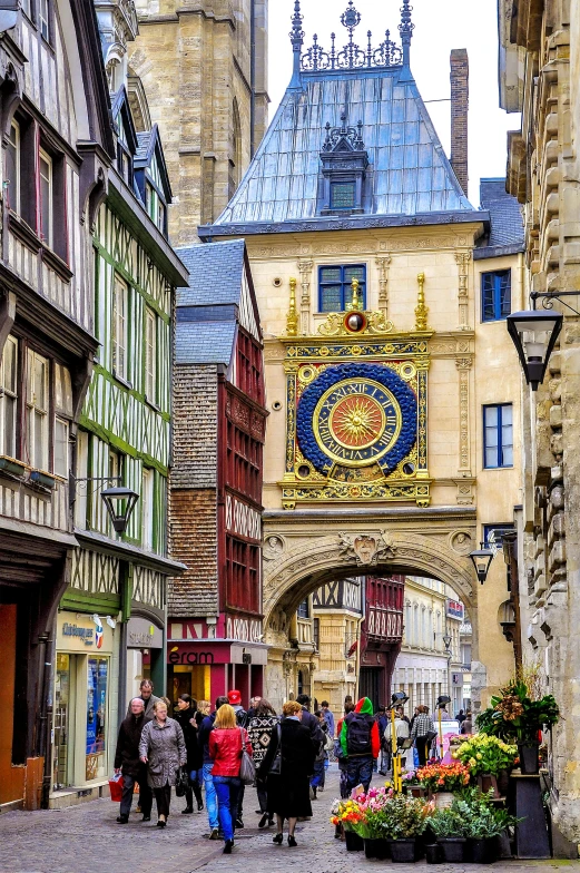 a group of people walking through a street below an old gate