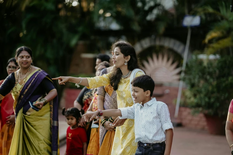 a woman pointing at a child with other people watching